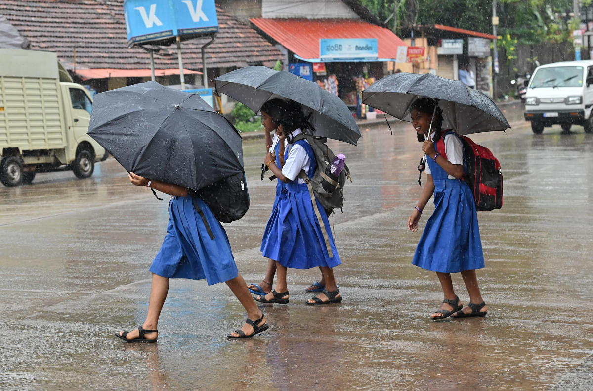 Students go to school amid rain in Mangaluru on Monday. Credit: DH Photo