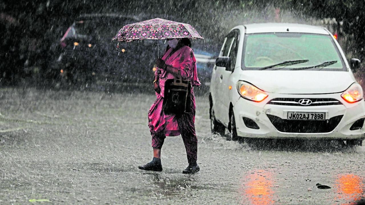 A woman holds an umbrella cross a street during heavy rain in Jammu, Saturday, Oct. 23, 2021. Credit: PTI Photo