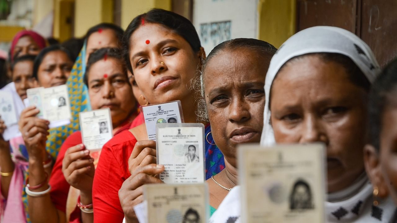 People wait in a queue at a polling station to cast their votes for Assembly by-elections. Credit: PTI Photo