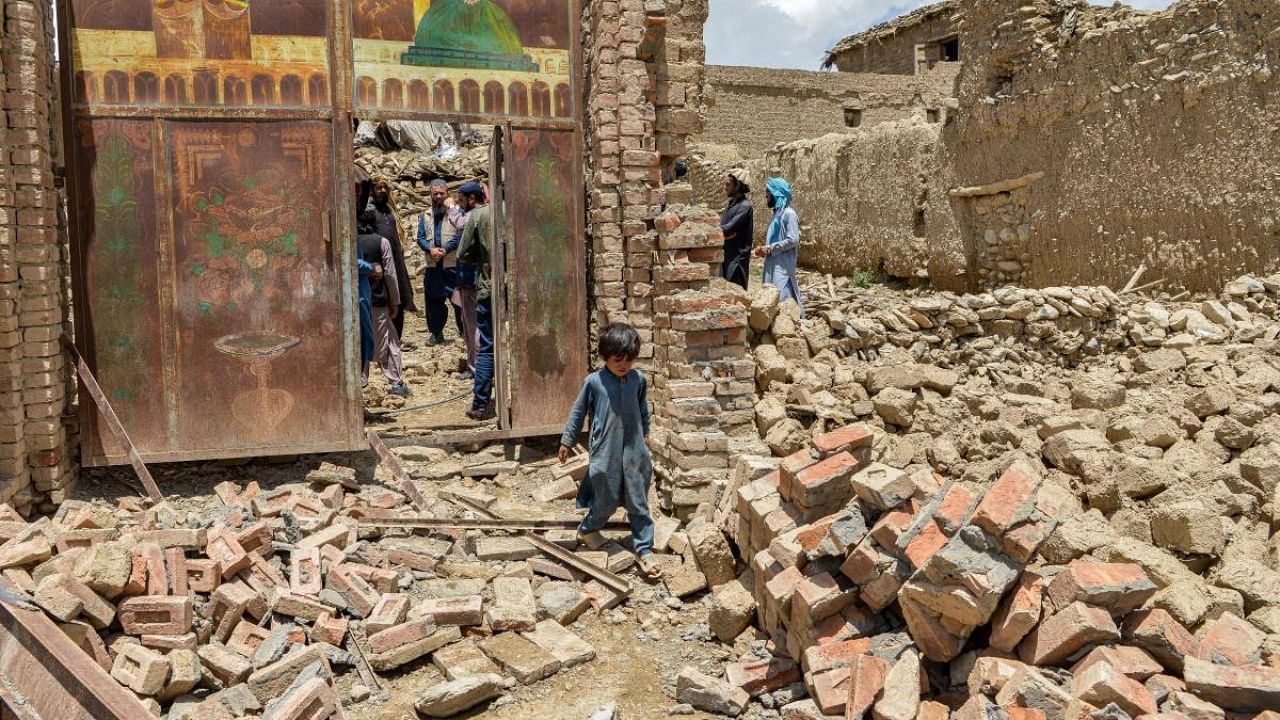 A child walks out from inside a gate of a house damaged by an earthquake in Bernal district, Paktika province. Credit: AFP Photo