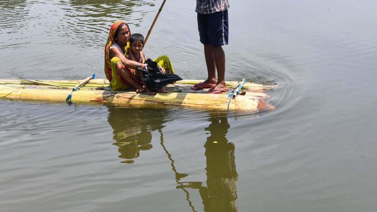 Villagers travel on a makeshift raft in flood waters at Hatibhangi village in Morigaon district, in Assam. Credit: AFP Photo