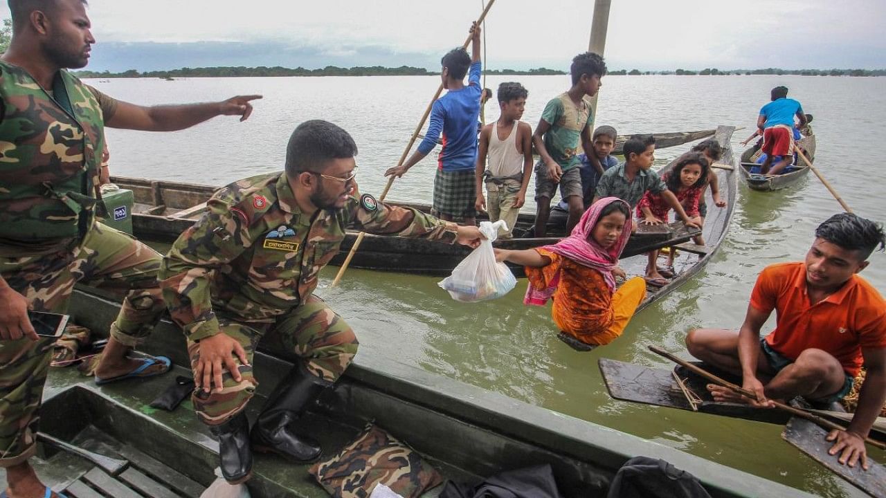 Soldiers provide food aid to the affected families in flooded residential areas following heavy monsoon rainfalls in Goyainghat. Credit: AFP Photo