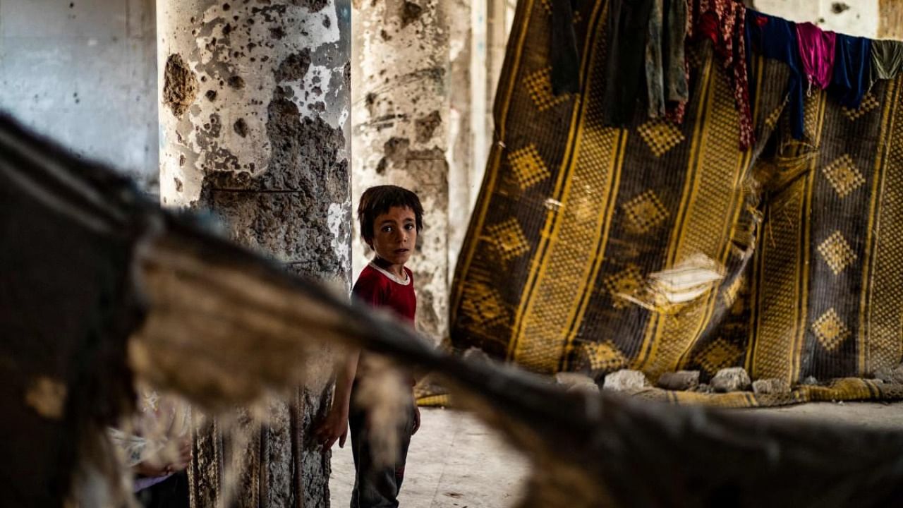 A Syrian boy, displaced with her family from Deir Ezzor, looks at the camera inside the damaged building where she is living in Syria's northern city of Raqa on June 18, 2022. Credit: AFP Photo