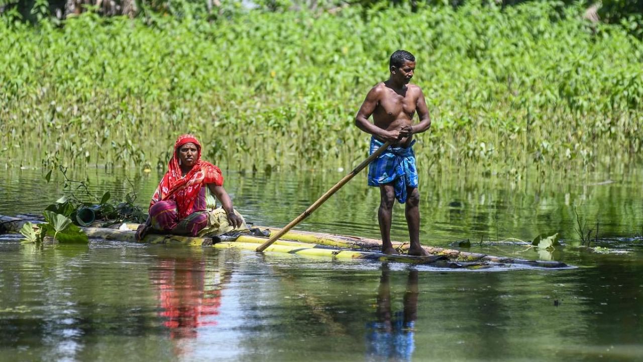 Villagers use a banana raft to cross a flooded field, at a village in Nagaon, Sunday, June 26, 2022. Credit: PTI Photo