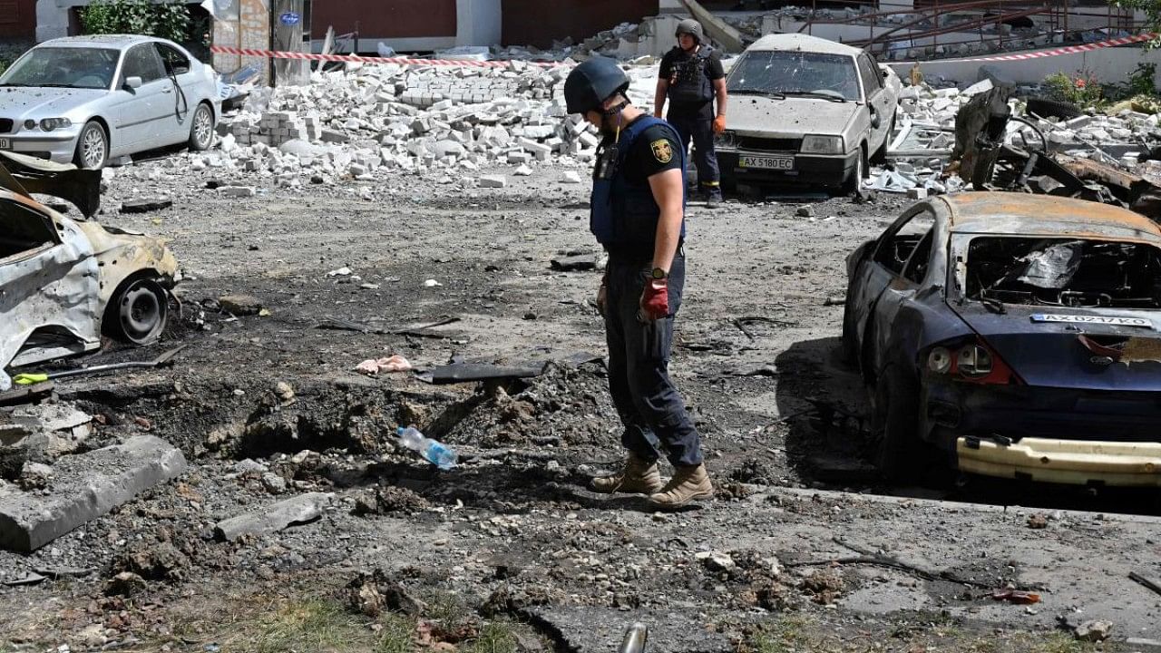 Officials examine a crater and the wreckage of vehicles after Russian missiles struck the courtyard of a multi-storey residential complex on the eastern outskirts of Kharkiv. Credit: AFP Photo