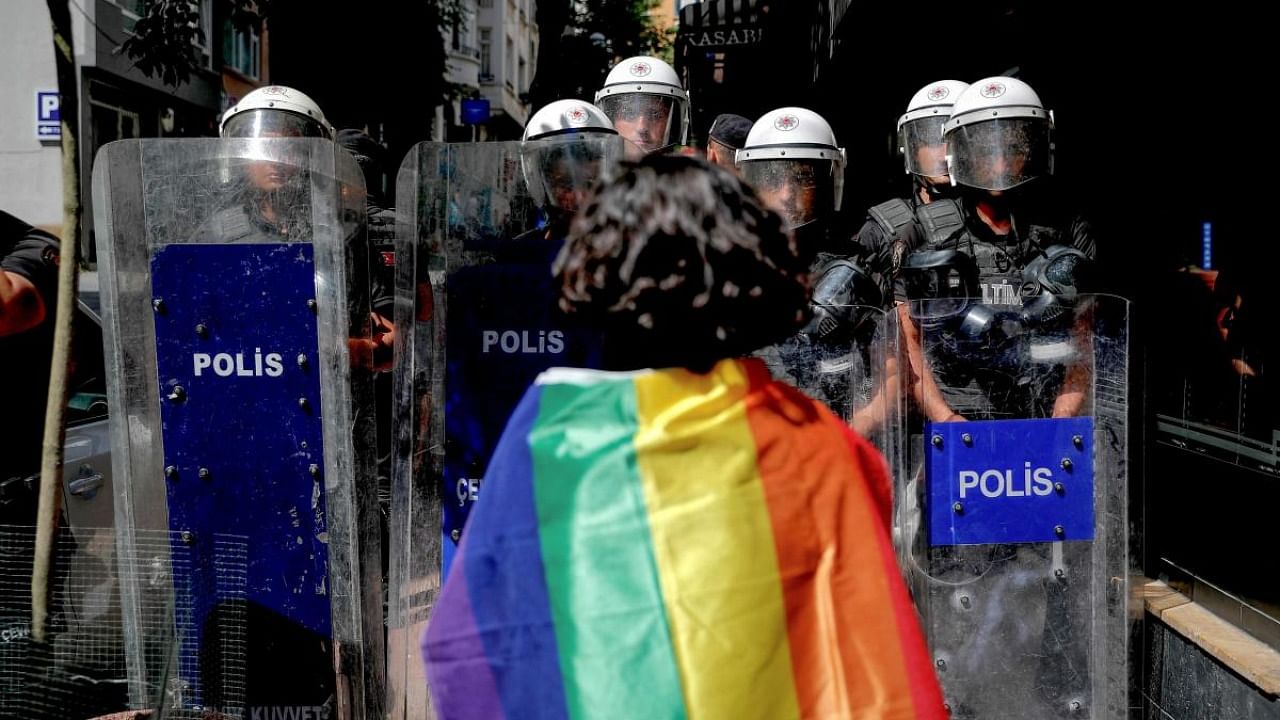 A participant faces riot policemen wearing a rainbow flag during a Pride march in Istanbul. Credit: AFP Photo