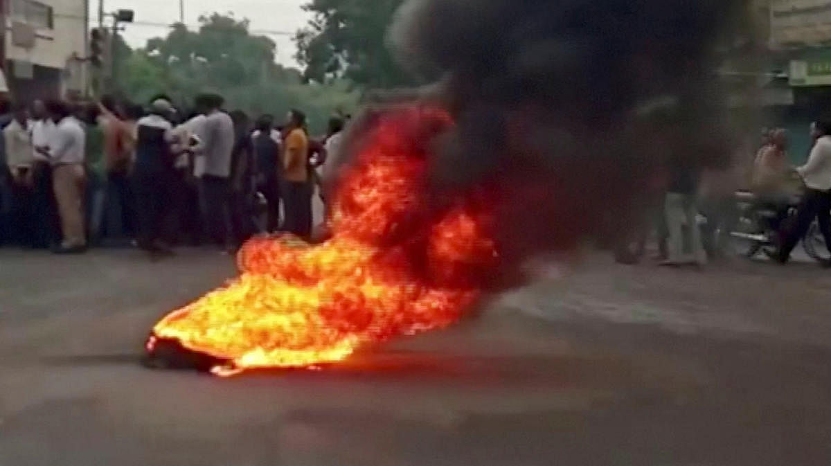 Smoke rises from a burning material while people gather on road as tensions rise after the killing of a Hindu man, in Udaipur, Rajasthan, India June 28, 2022 in this still image obtained from a handout video. Credit: ANI/Handout via Reuters