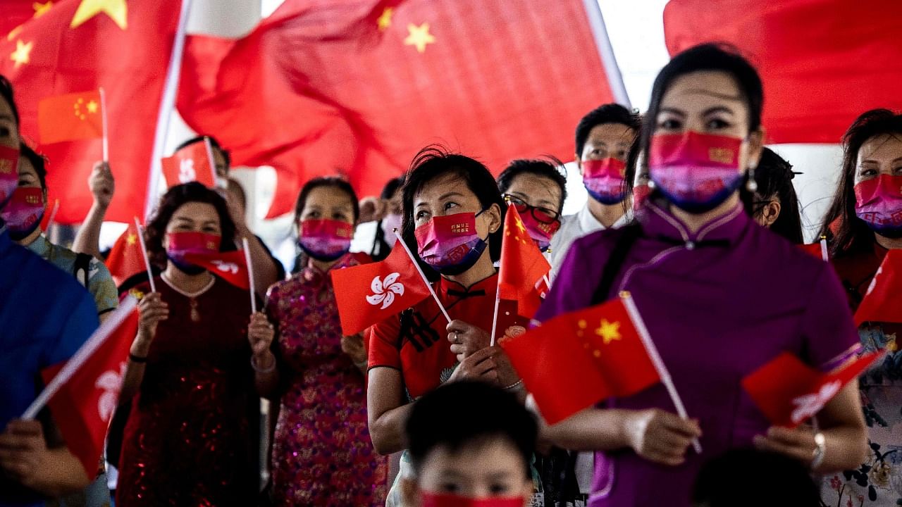 People hold the Hong Kong and Chinese flags while singing to celebrate the 25th anniversary of the city's handover from Britain to China, in Hong Kong. Credit: AFP Photo