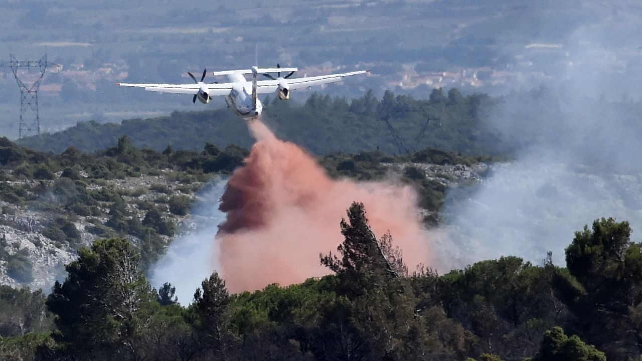 A Dash firefighting aircraft drops flame retardant onto a wildfire at the Opoul mountain range. Credit: AFP Photo