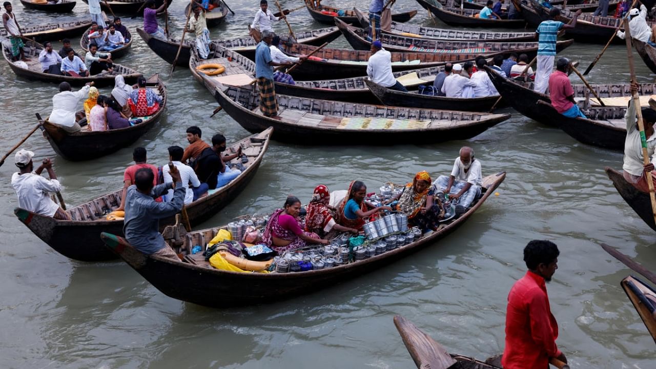 Women cross the river Buriganga with lunchboxes on a boat to deliver to their customers in Dhaka, Bangladesh, July 2, 2022. Credit: Reuters Photo