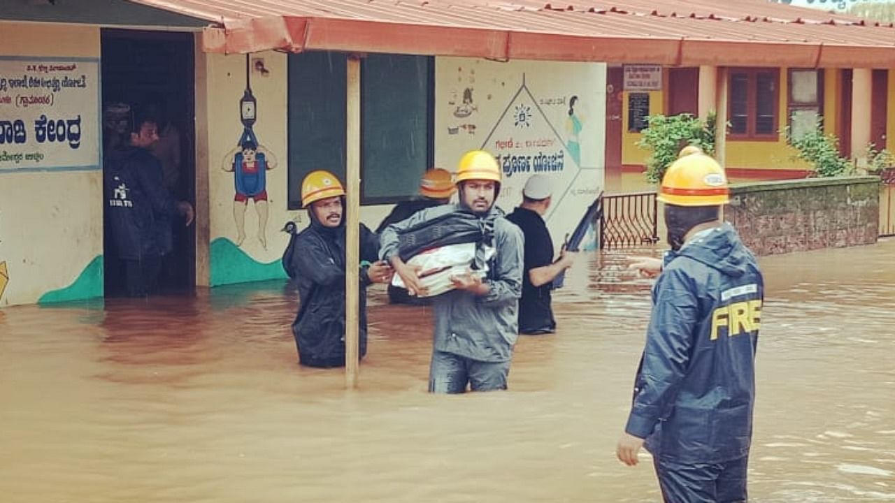 Fire and emergency service personnel shifting materials from a flooded anganwadi centre at Ucchila Gudde. Credit: Special arrangement