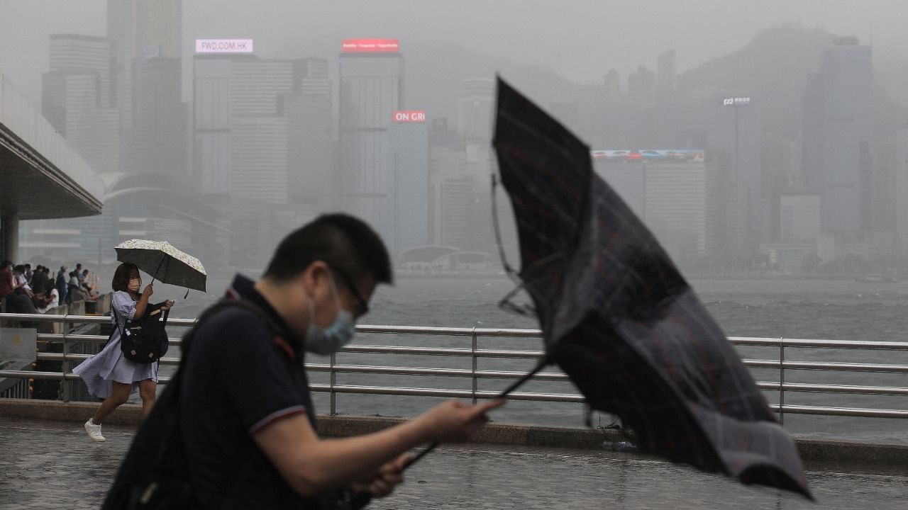 People hold umbrellas in the rain at a waterfront, amid a typhoon warning in Hong Kong. Credit: Reuters Photo