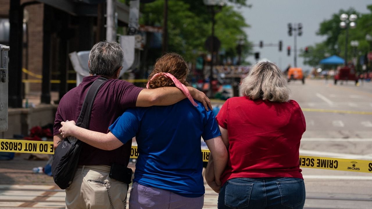 A family embraces while observing the scene of a mass shooting at a July 4th Parade in downtown Highland Park, Illinois. Credit: AFP Photo