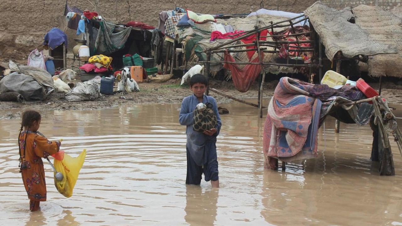 Children wade through a flooded area after a monsoon rainfall in Quetta. Credit: AFP Photo