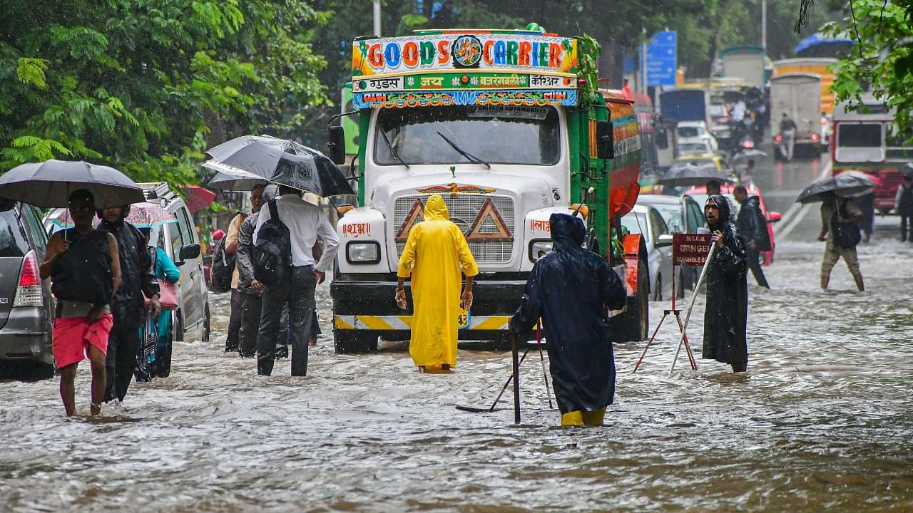 Commuters wade through a waterlogged road following Monsoon rains, in Mumbai. Credit: PTI Photo