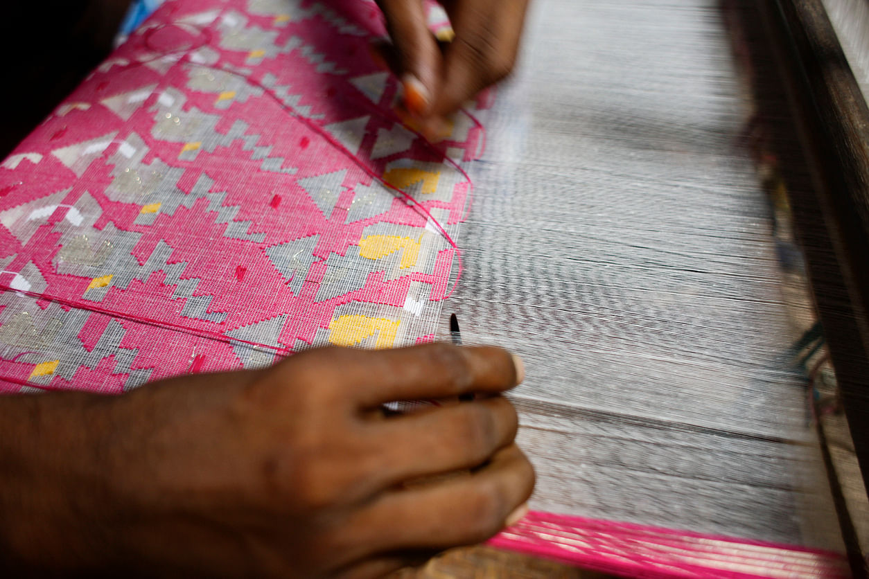 Handloom weaver weaves Jamdani saree on a traditional wooden hand weaving loom. Credit: Suvra Kanti Das/iStock Photo