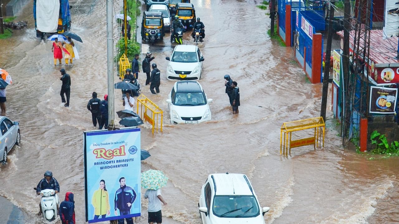 Vehicles and pedestrians wade through a waterlogged road during monsoon rainfall, in Mangaluru. Credit: PTI Photo