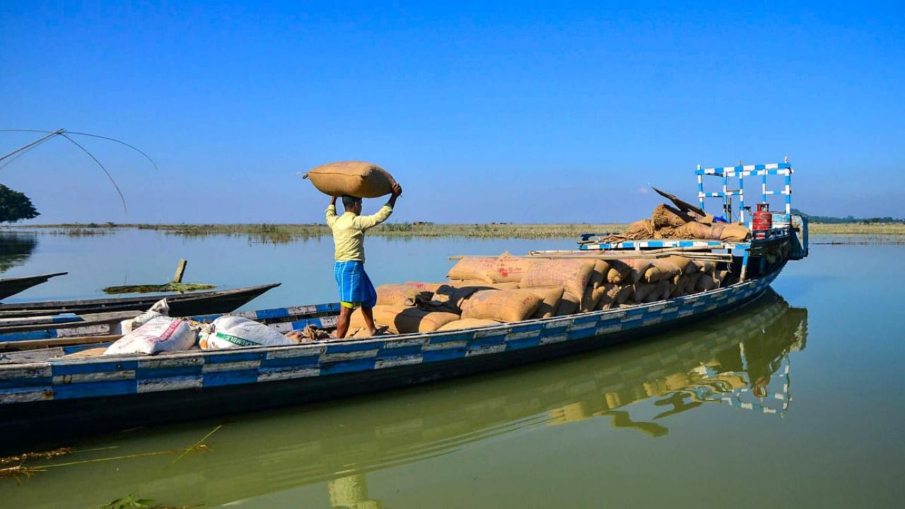 A villager loads rice sacks on a boat for flood-affected people, at Chanukah village in Morigaon district. Credit: PTI Photo