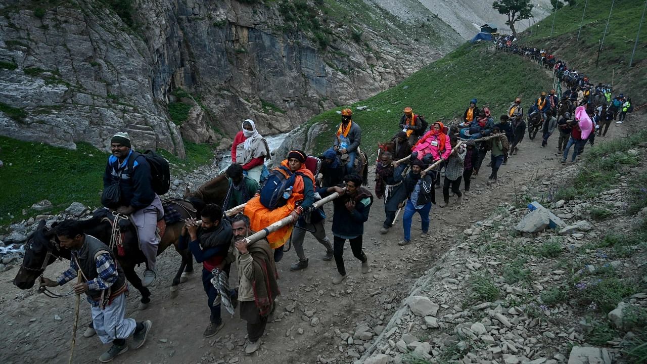 Hindu devotees make their way on foot, riding horses and carried by porters along a mountain path during their pilgrimage to the cave shrine of Amarnath. Credit: AFP Photo