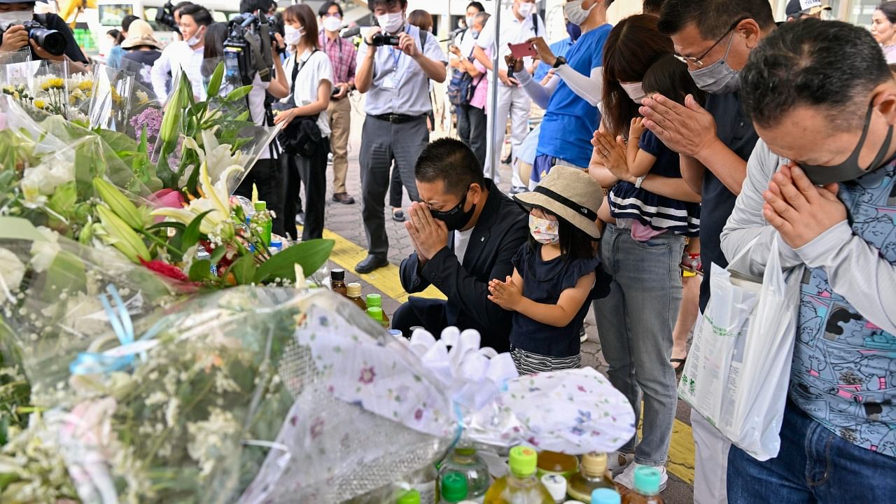 People pray at a makeshift memorial near the scene where the former Prime Minister Shinzo Abe was shot. Credit: AP Photo