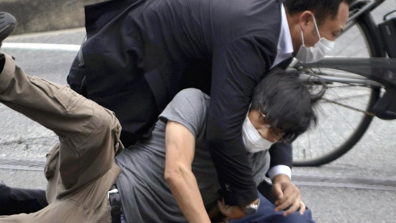 Tetsuya Yamagami, bottom, is detained near the site of gunshots in Nara Prefecture, western Japan on July 8. Credit: AP Photo