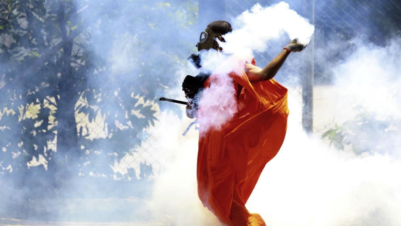 A man throws back a tear gas shell after it was fired by police to disperse the protesters in Colombo. Credit: AP/PTI Photo