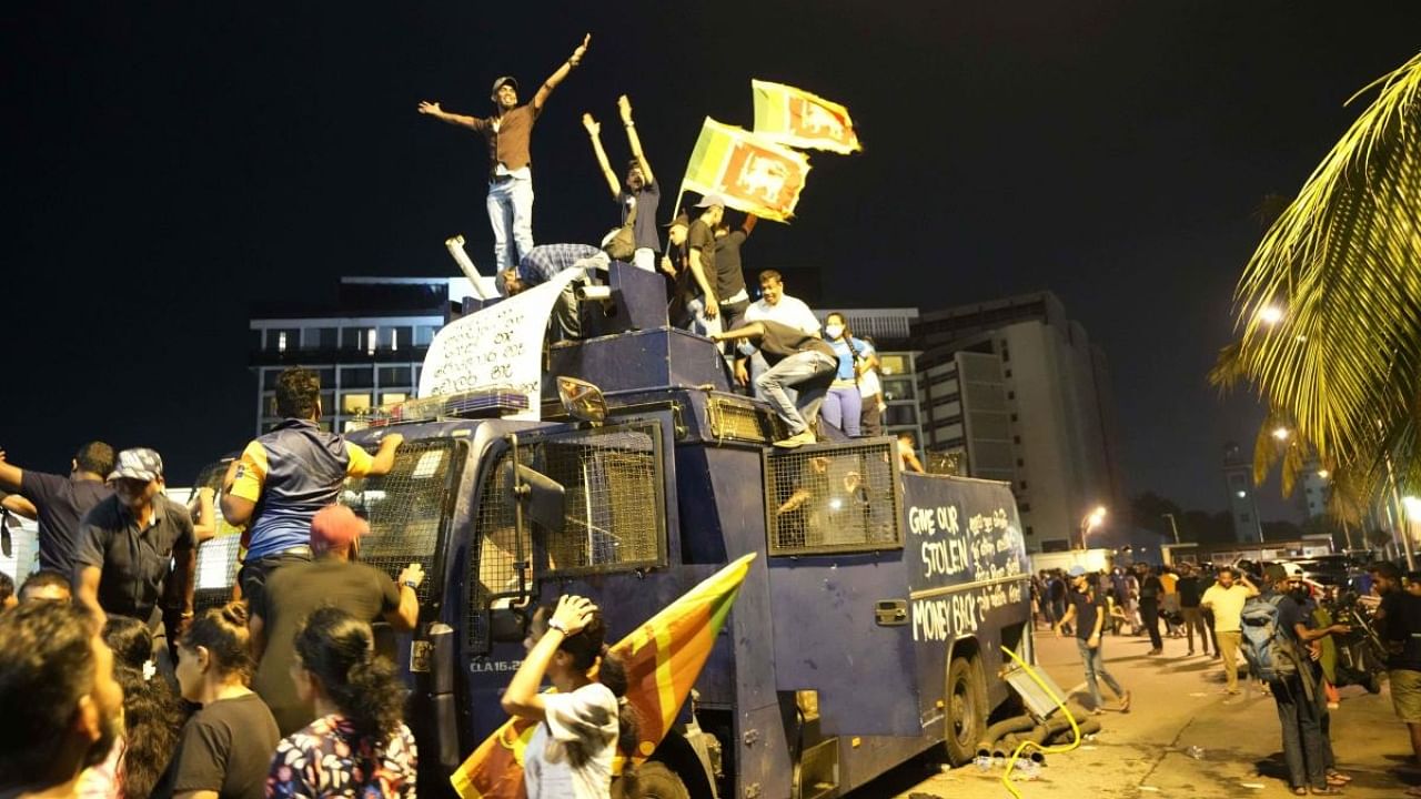 Protesters stand on a vandalised police water canon truck and shout slogans at the entrance to president's official residence in Colombo, Sri Lanka. Credit: AP Photo