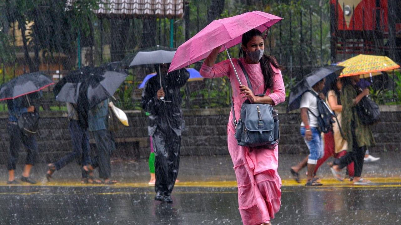 Commuters make their way through a street amidst heavy rainfall in Mumbai on July 13, 2022. Credit: AFP Photo