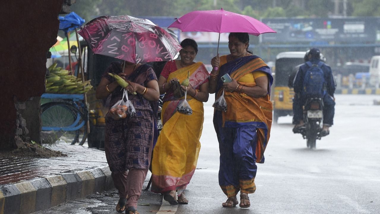People shelter under umbrella during a monsoon rainfall in Hyderabad. Credit: AFP Photo