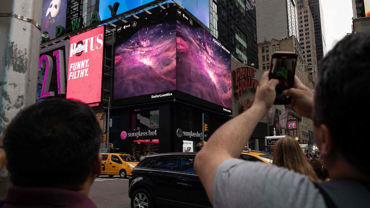  person takes a video of the gians screens displaying images captured by The James Webb Space Telescope. Credit: AFP Photo