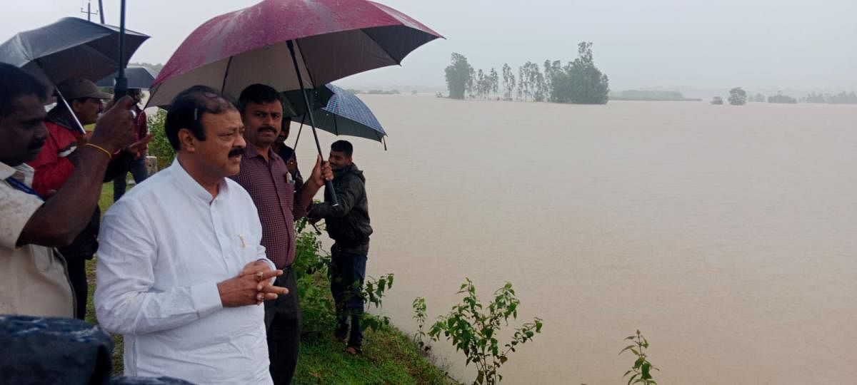 District In-charge Minister K C Narayana Gowda looks at the inundated farms in Sagar taluk on Thursday, marooned due to copious rains that have been lashing the region for the past one week. Credit: DH Photo