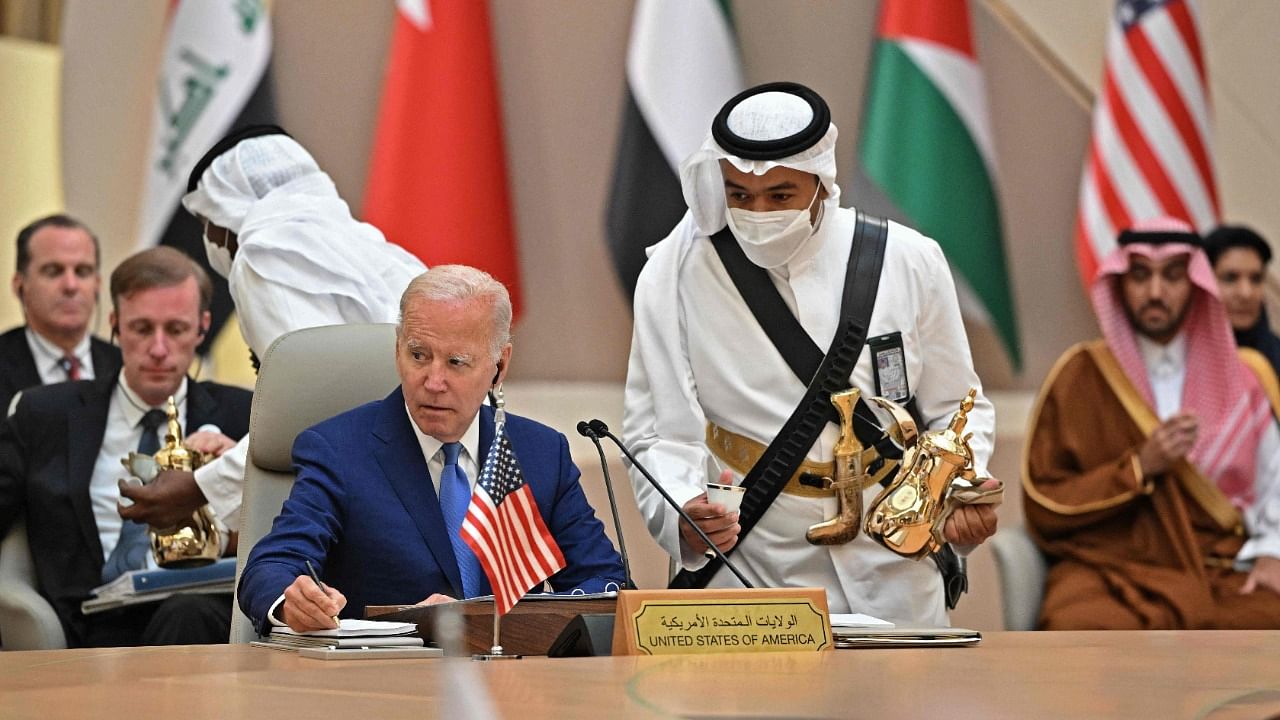 US President Joe Biden takes notes while an usher serves coffee during the Jeddah Security and Development Summit (GCC+3) at a hotel in Saudi Arabia's Red Sea coastal city of Jeddah. Credit: AFP Photo
