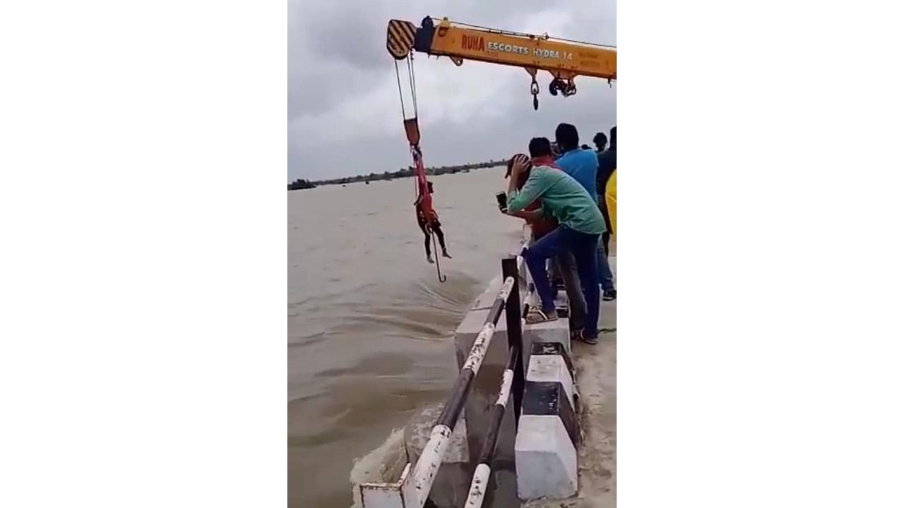 A youth tied to a crane, gets into the swollen river, risking his life to lift the sluice gates of Gurjapura barrage in Shaktinagar, Raichur. Credit: Special arrangement
