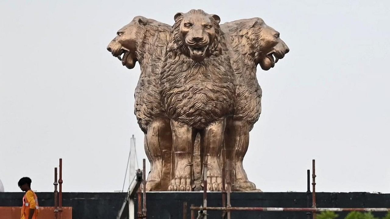 A worker walks past the newly inaugurated 'National Emblem' installed on the roof of the new Indian parliament building in New Delhi. Credit: AFP File Photo