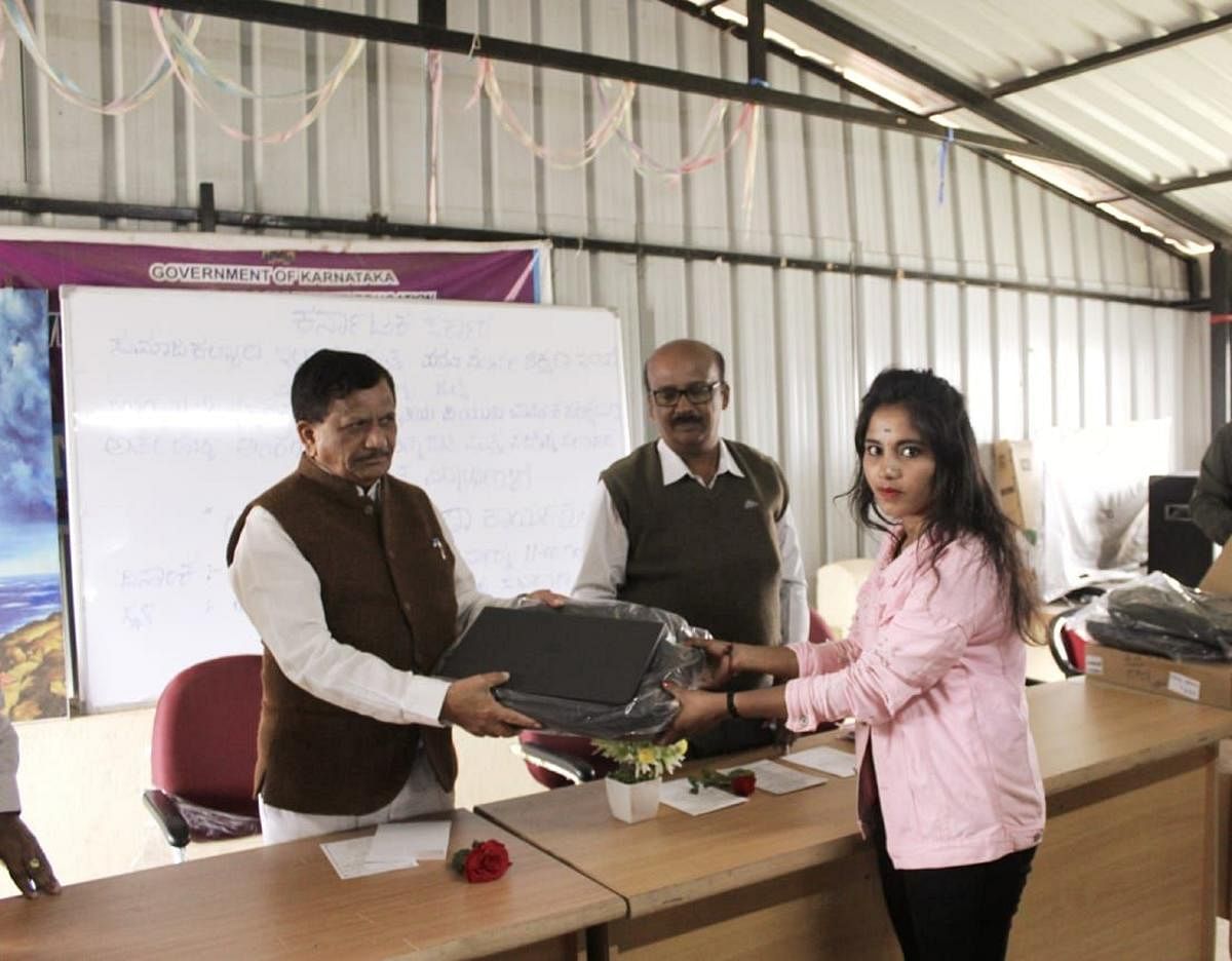 MLA K G Bopaiah hands over a laptop to a student at the Government First Grade College in Madikeri. Credit: DH Photo