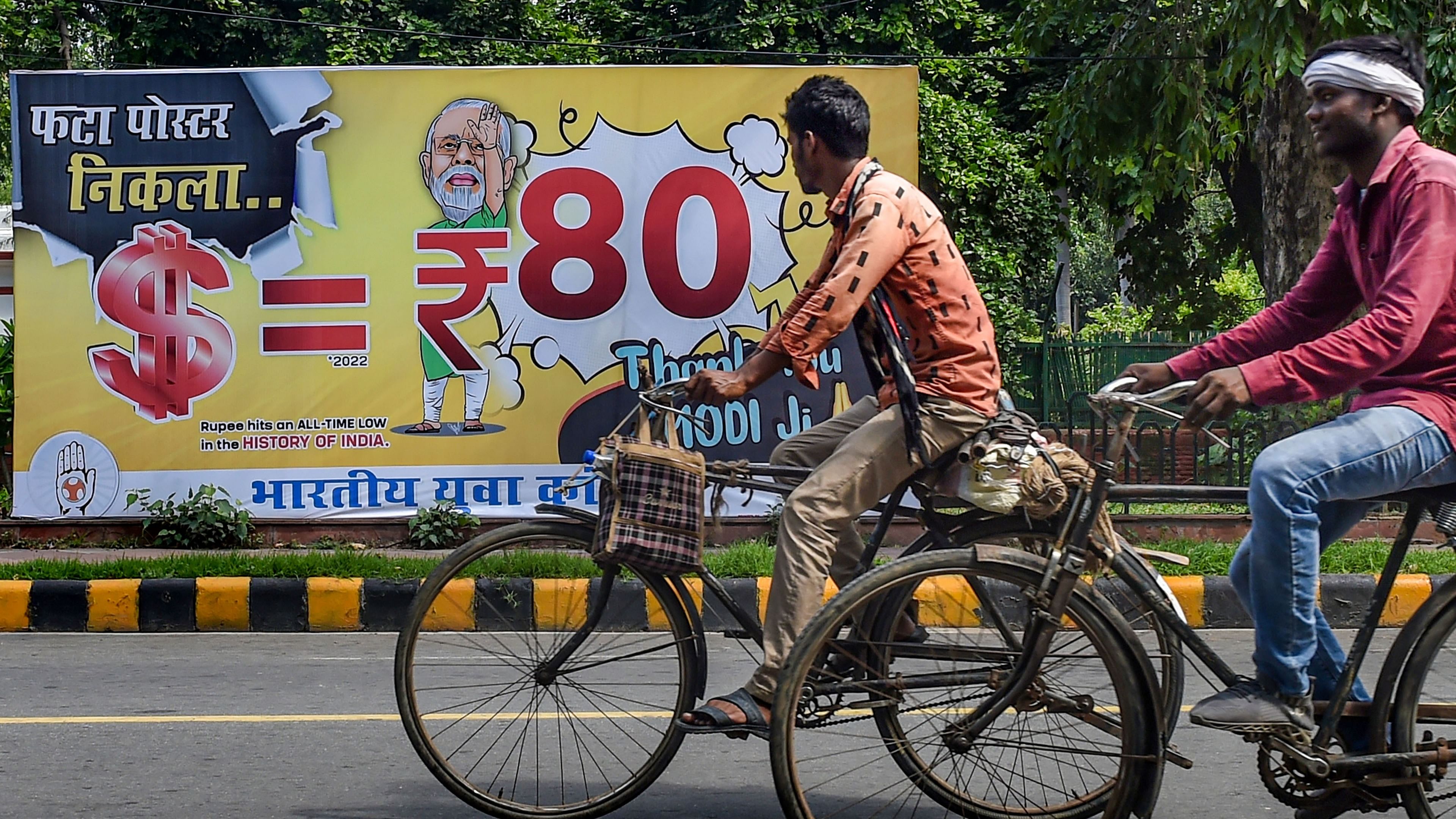  People move past a hoarding, depicting the Indian rupee's depreciation against the US currency, put up by Indian Youth Congress, in New Delhi. Credit: PTI File Photo