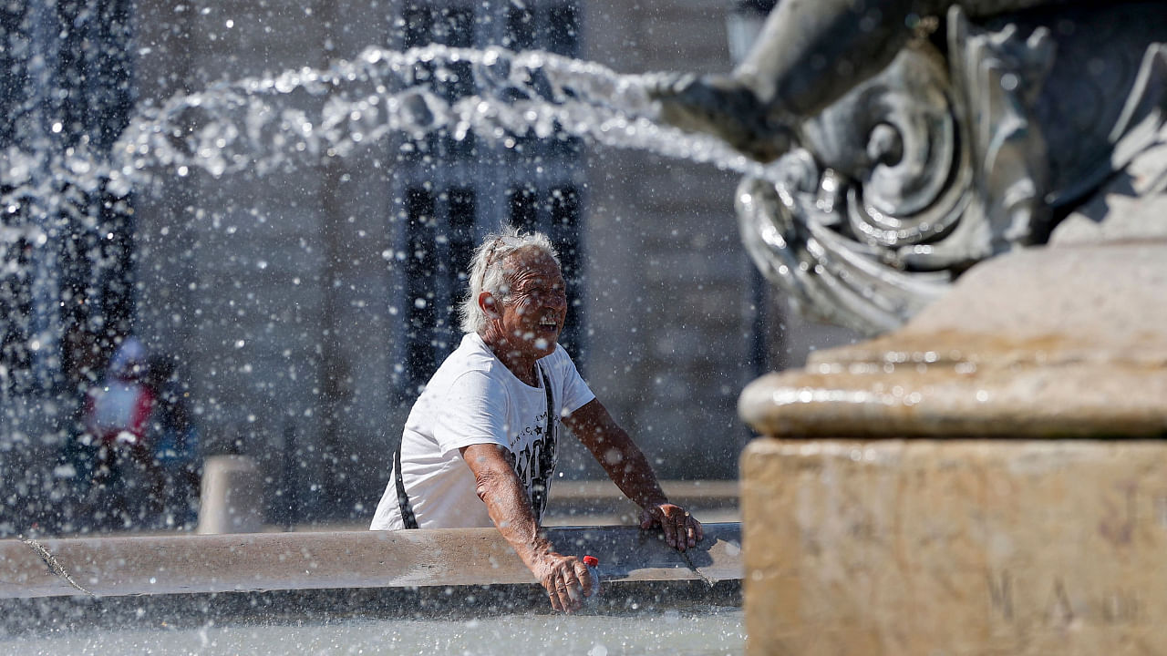 A man puts his bottle in the water of a fountain to cool it down during a heatwave, on July 18, 2022 in Bordeaux. Credit: AFP Photo