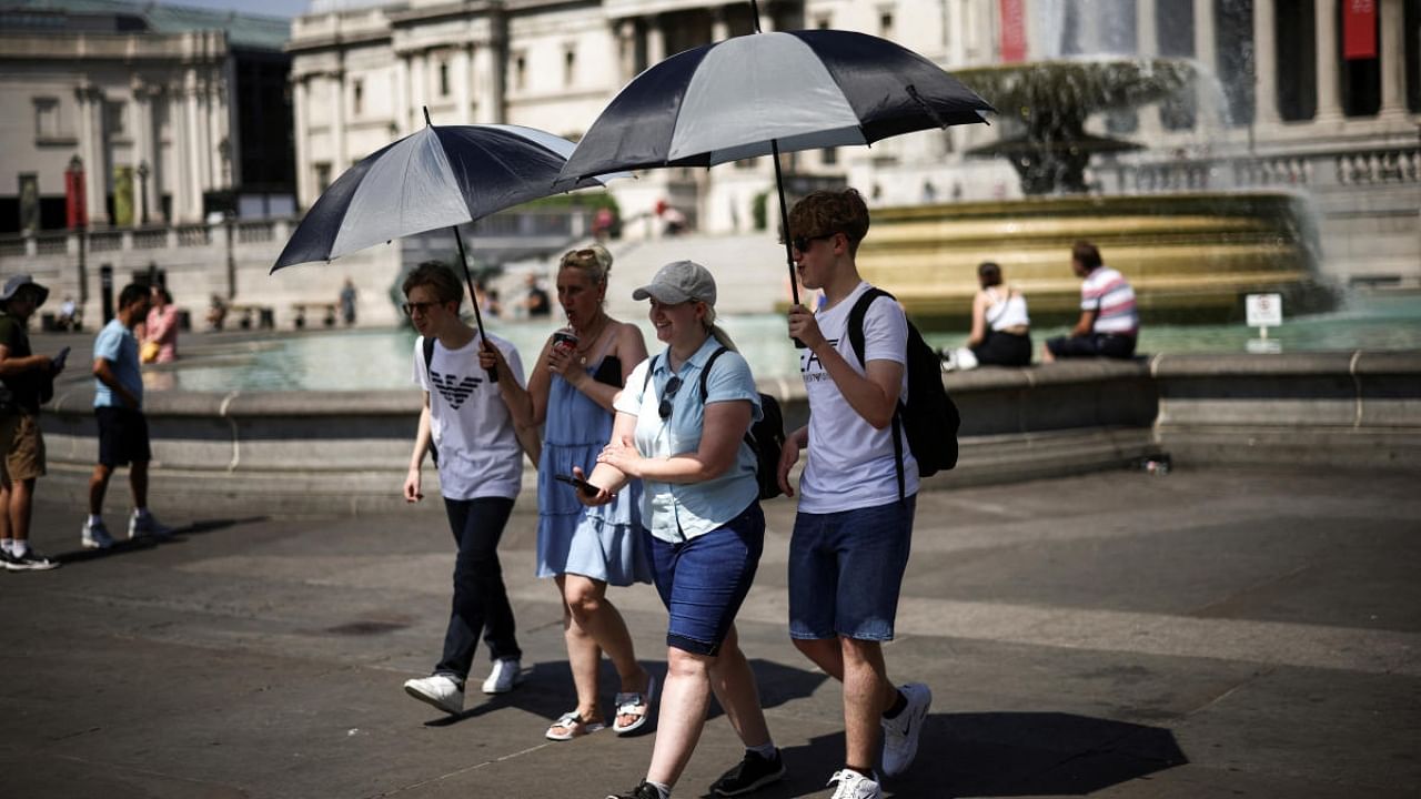 People carry umbrellas to hide in their shadow during a heatwave, at Trafalgar Square in London, Britain, July 19, 2022. Credit: Reuters Photo