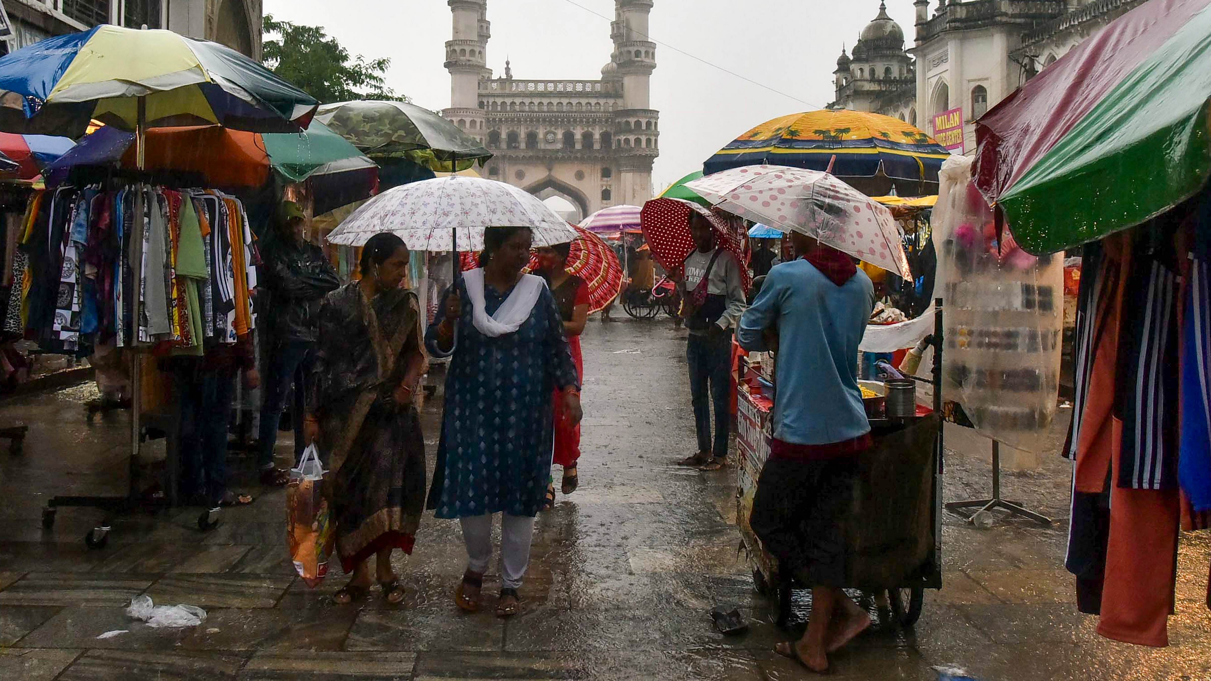 People walk during monsoon rain in the backdrop of the historic Charminar, in Hyderabad. Credit: PTI Photo