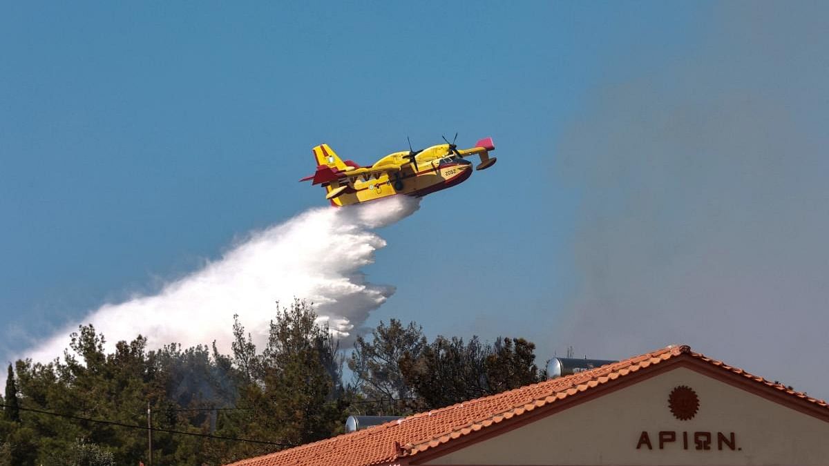 A canadair firefighting plane drops water at the wildfire approaching homes and hotels at Vatera coastal resort on the eastern island of Lesbos. Credit: AFP Photo