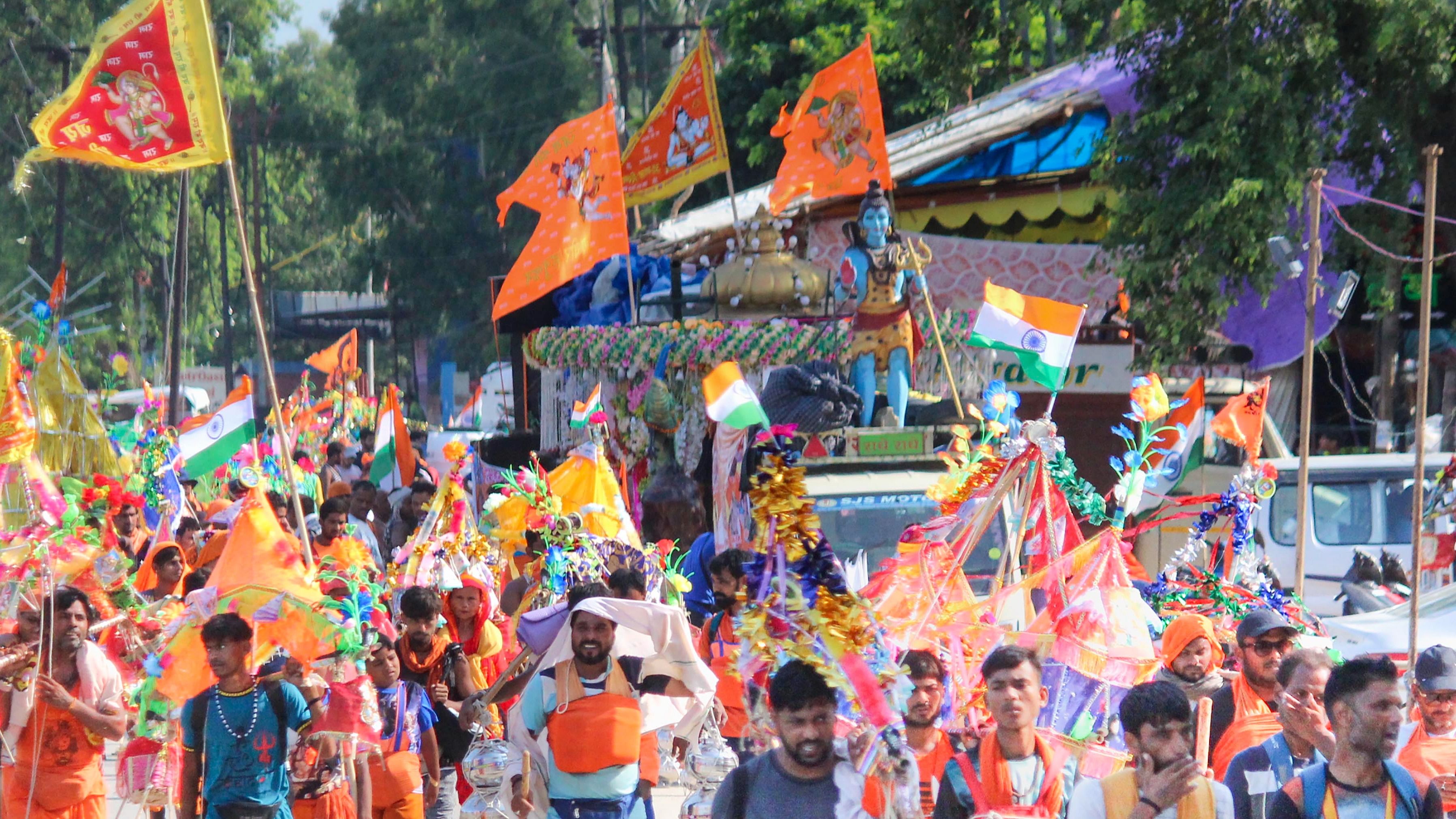 Kanwariyas (Lord Shiva devotees) walk down the road during their pilgrimage in the holy month of 'Shravan', in Meerut, Sunday, July 24, 2022. Credit: PTI Photo