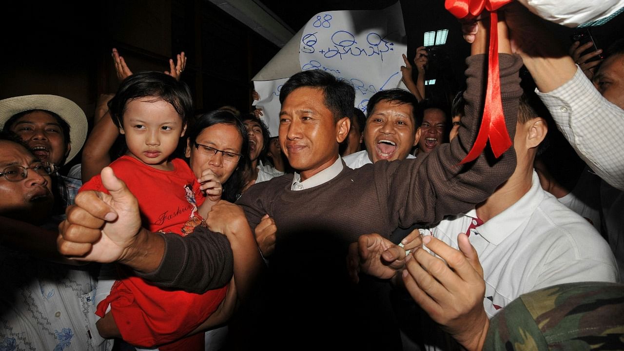 Kyaw Min Yu (C), known as Jimmy, and his wife Ni Lar Thein (L) holding her child, both members of the 88 Generation student group, celebrating upon their arrival at Yangon international airport following their release from detention. Credit: AFP Photo