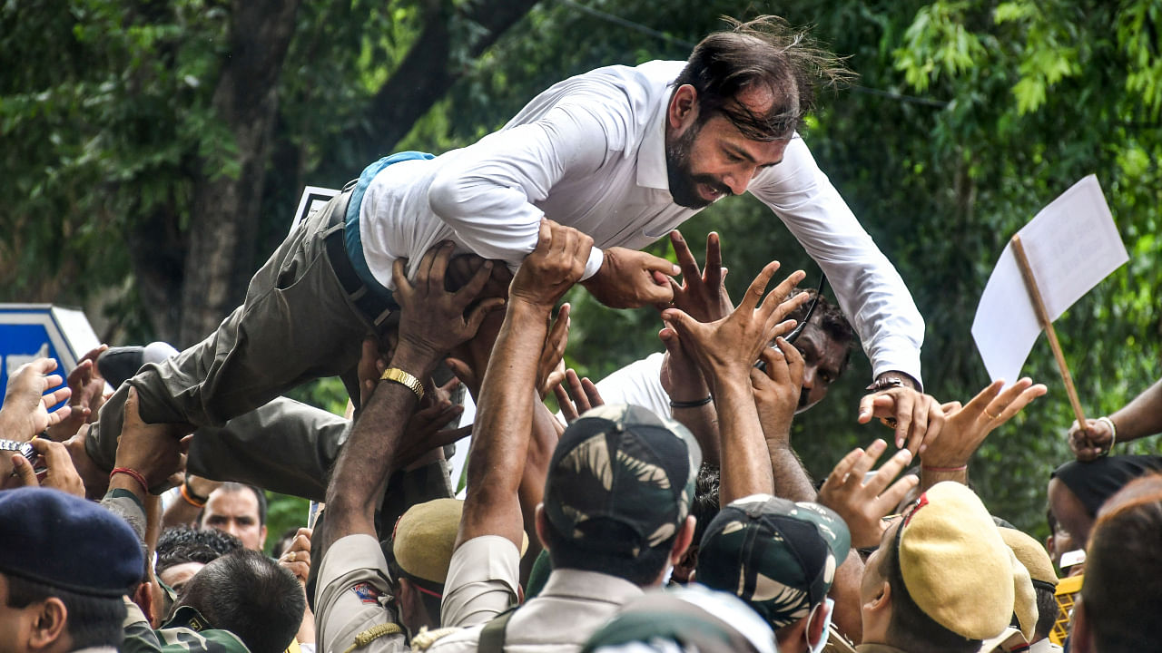 Security personnel try to stop a BJP activist who was taking part in a protest against the Delhi Government's excise policy, at ITO in New Delhi, July 25, 2022. Credit: PTI Photo