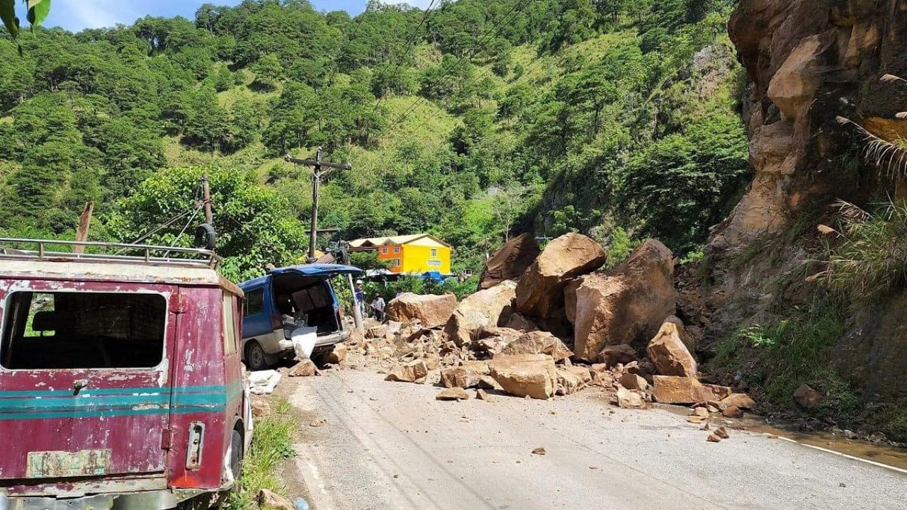 Boulders and a damaged vehicle (C) blocking a road following a landslide along Halsema Highway in the municipality of Bontoc, Mountain Province, after a 7.0-magnitude earthquake hit the northern Philippines. Credit: AFP Photo