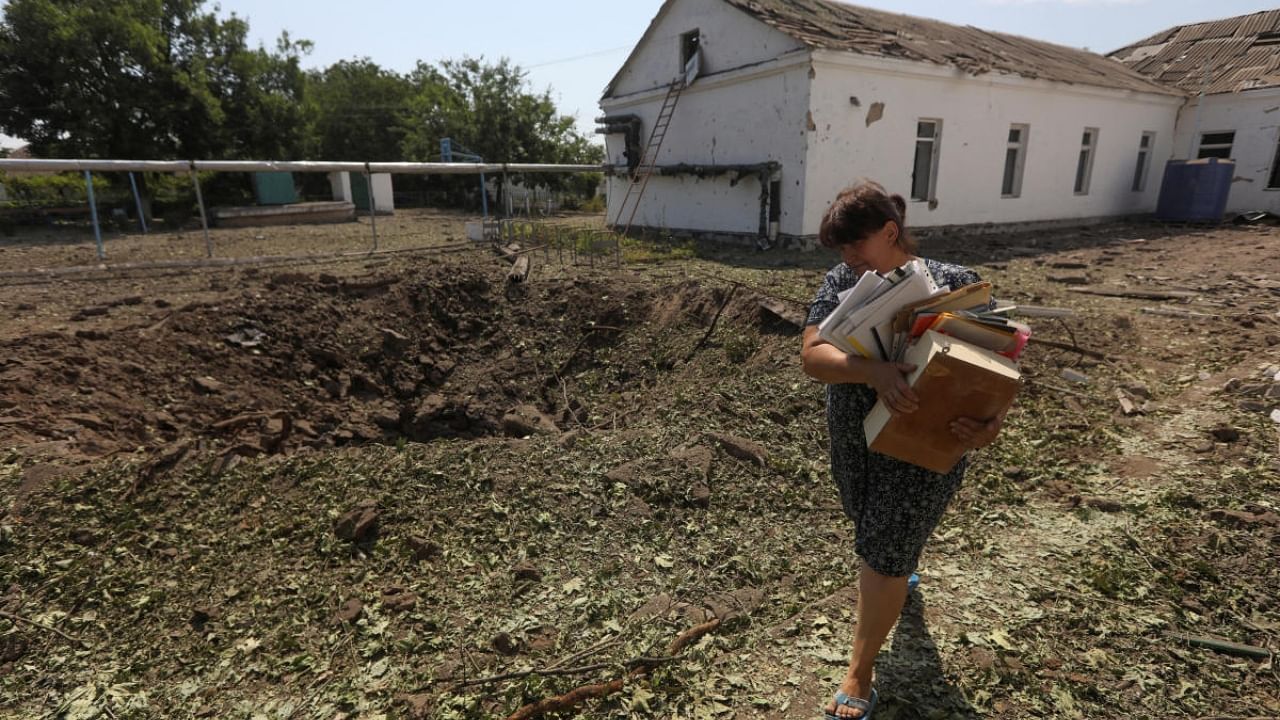 An employee carries out documents from a school building damaged by a Russian missile strike, as Russia's attack on Ukraine continues, in Mykolaiv, Ukraine July 28, 2022. Credit: Reuters Photo
