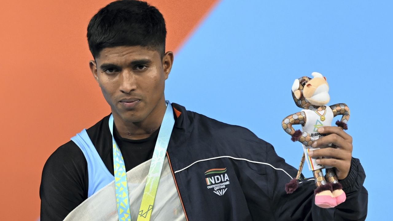 Sanket Sargar atop the podium poses after winning the silver medal in the men's 55kg category weightlifting even. Credit: PTI Photo