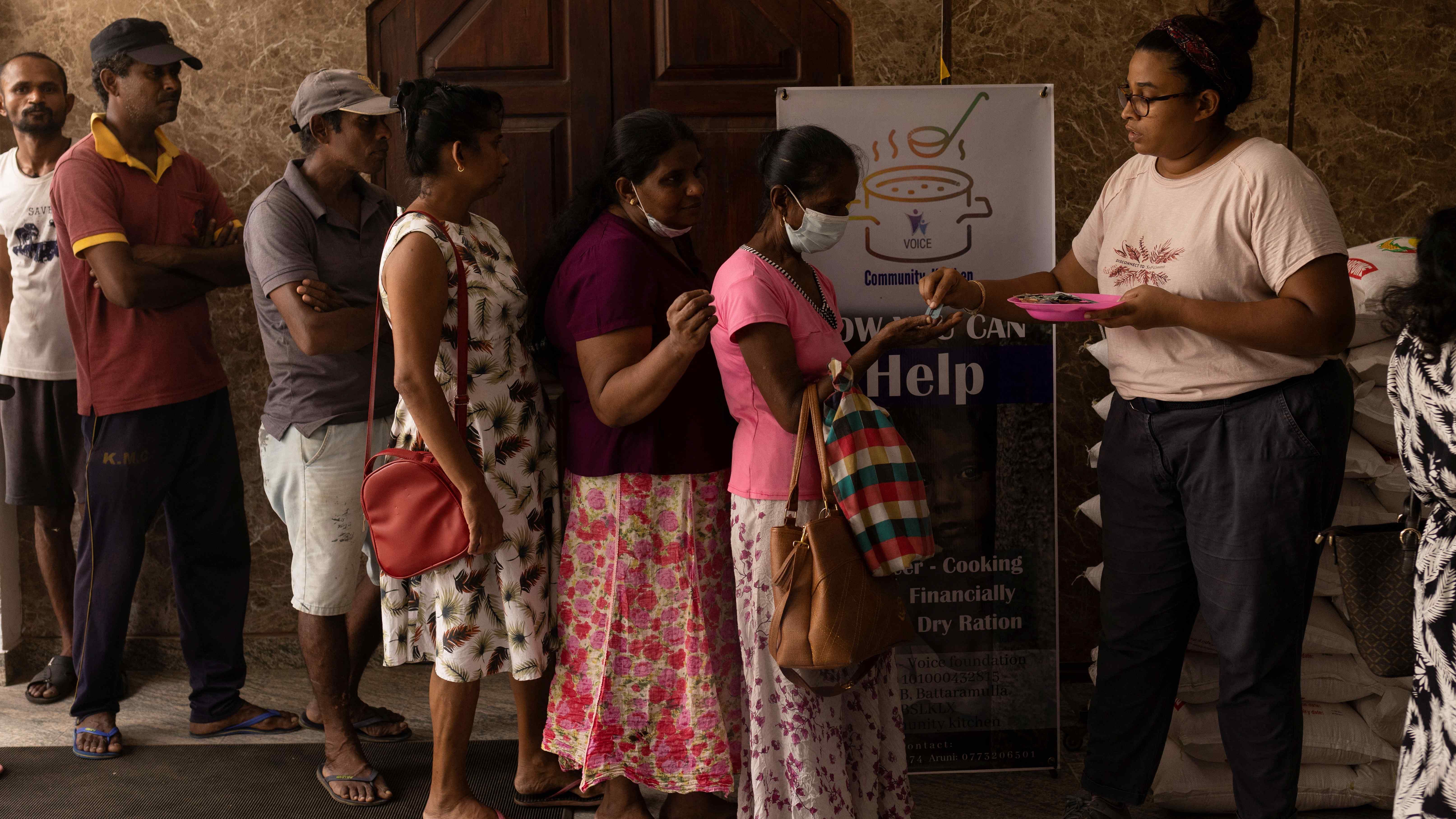 Aru de Silva, 36, a volunteer, distributes tokens for free food in Sri Lanka. Credit: Reuters Photo