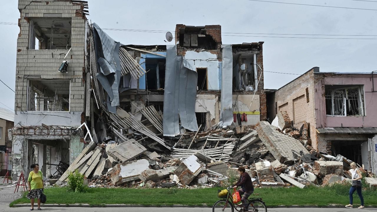  Pedestrians walk past a destroyed store in the city of Okhtyrka, Sumy region. Credit: AFP Photo