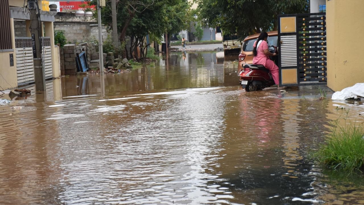 A resident riding a scooter through a waterlogged street at Rajiv Gandhi Nagar on Wednesday. Credit: DH Photo/B K Janardhan