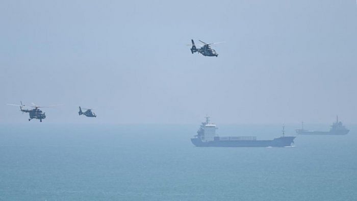 Tourists look on as a Chinese military helicopter flies past Pingtan island, one of mainland China's closest point from Taiwan, in Fujian province on August 4, 2022, ahead of massive military drills off Taiwan following US House Speaker Nancy Pelosi's visit to the self-ruled island. Credit: AFP Photo
